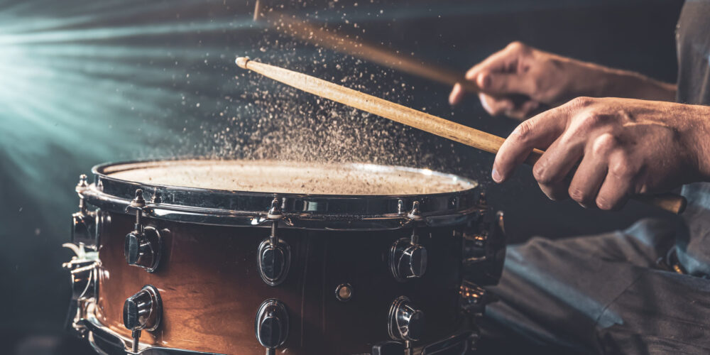 Close-up of a drummer playing a snare drum with splashing water.
